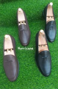 brown and black mens loafers on a green carpet