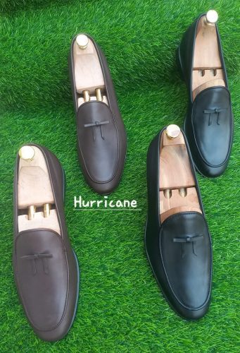 brown and black mens loafers on a green carpet